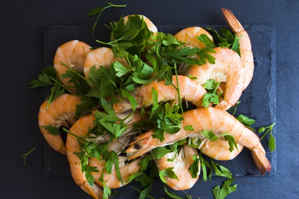 Camarones con perejil sobre pizarra de piedra — Foto de Stock