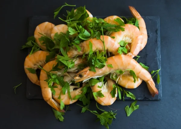 Camarones con perejil sobre pizarra de piedra — Foto de Stock