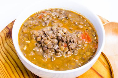 Ahşap tepside ve beyaz arka planda lezzetli mercimekler.