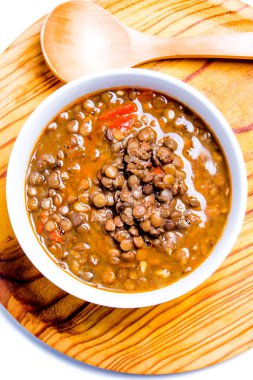 Ahşap tepside ve beyaz arka planda lezzetli mercimekler.