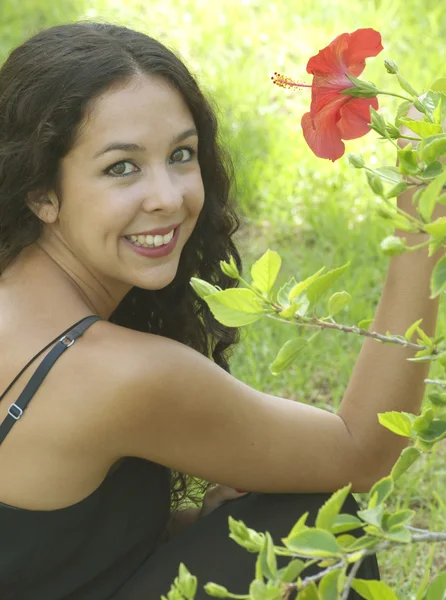 Красивая женщина в парке с красным цветком — стоковое фото