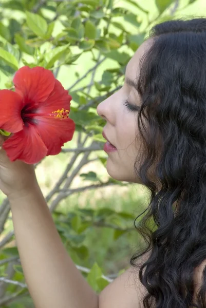 Mulher bonita em um parque com flor vermelha — Fotografia de Stock