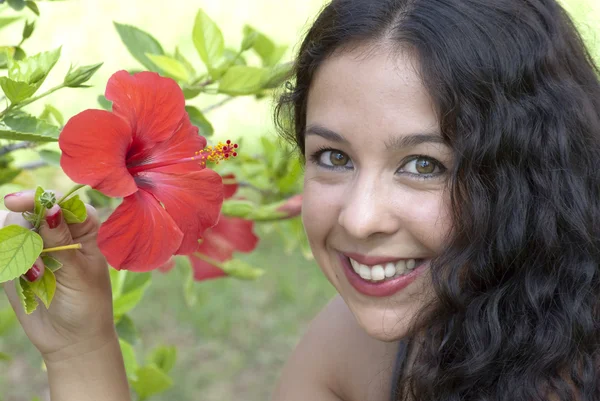 Mooie vrouw in een park met rode bloem — Stockfoto