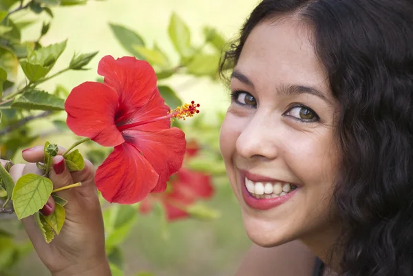 Mooie vrouw in een park met rode bloem — Stockfoto