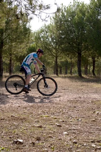 Ciclista em corridas de mountain bike fazendo uma carreira no campo — Fotografia de Stock