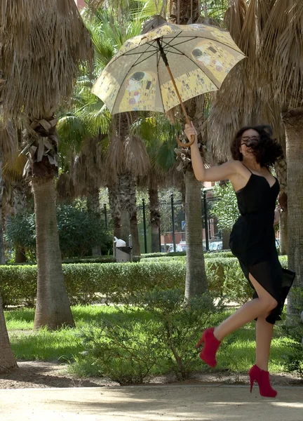 美しい女性の傘を持つ公園でジャンプ — ストック写真