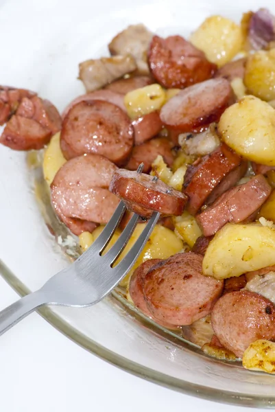 Placa de trozos de salchicha, patatas, ajo y carne con un pastel — Foto de Stock