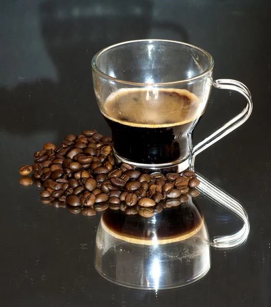 Taza de café y granos de café en un espejo —  Fotos de Stock