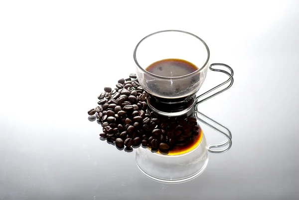 Taza de café y granos de café en un espejo — Foto de Stock