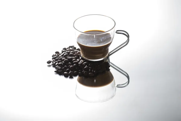 Кофейная чашка и кофейные зёрна на зеркале — стоковое фото