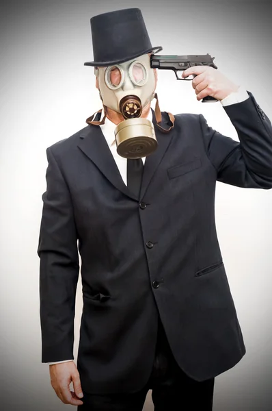 Geschäftsmann mit Gasmaske, der eine Waffe auf seinen Kopf richtet, als — Stockfoto