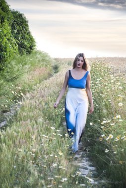 Bir buğday alanında bir yolda güzel sarışın kadın 