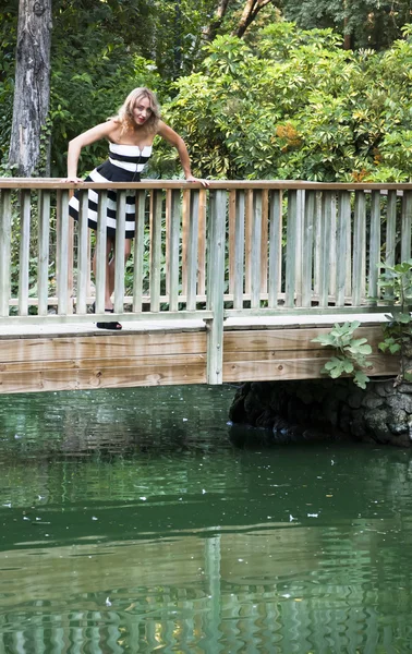 Hermosa mujer en un puente de madera en el parque — Foto de Stock