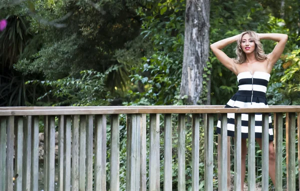 Hermosa mujer en un puente de madera en el parque — Foto de Stock