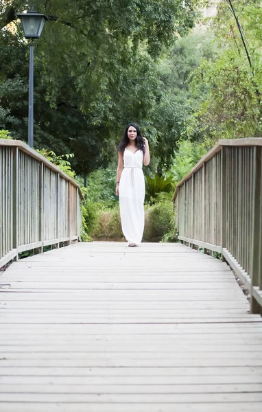 Mulher bonita em uma ponte de madeira no parque — Fotografia de Stock