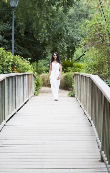 Mulher bonita em uma ponte de madeira no parque — Fotografia de Stock