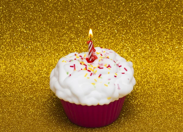 Cupcake com uma vela acesa sobre fundo brilhante — Fotografia de Stock