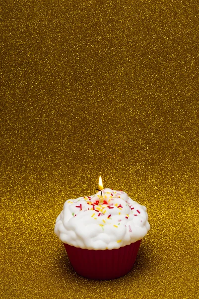 Cupcake con una vela encendida sobre fondo brillante — Foto de Stock