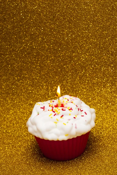 Cupcake con una vela encendida sobre fondo brillante — Foto de Stock