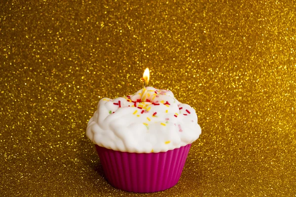 Cupcake com uma vela acesa sobre fundo brilhante — Fotografia de Stock