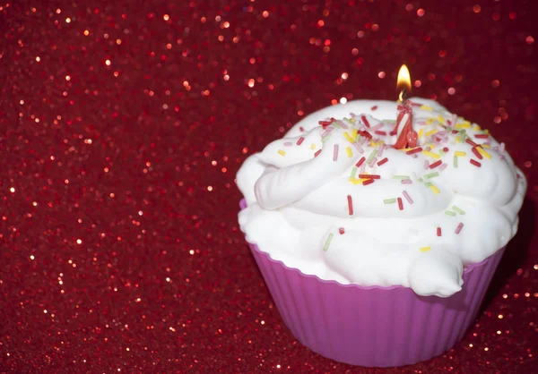 Cupcake con una candela accesa su sfondo rosso brillante — Foto Stock