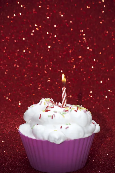 Parlak kırmızı bir arka plan üzerinde yanan bir mum ile cupcake — Stok fotoğraf