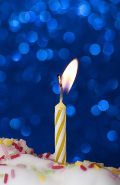 Parlak mavi arka plan üzerinde yanan bir mum ile cupcake
