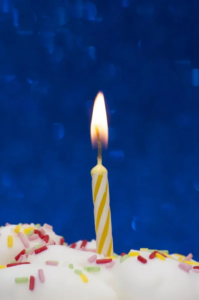 Cupcake con una candela accesa su sfondo blu brillante — Foto Stock