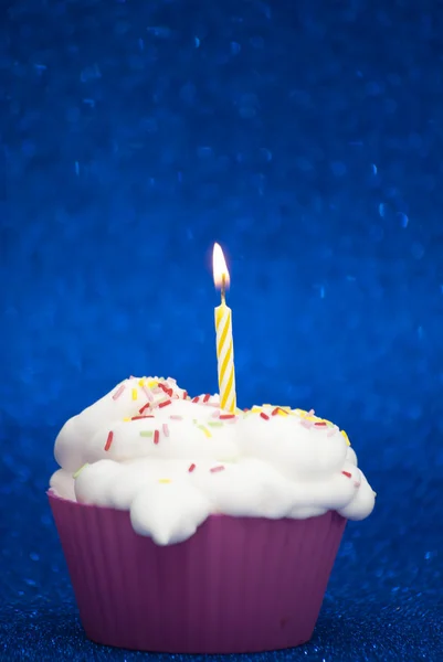 Parlak mavi arka plan üzerinde yanan bir mum ile cupcake — Stok fotoğraf
