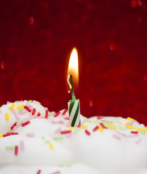 Cupcake com uma vela acesa sobre fundo vermelho brilhante — Fotografia de Stock