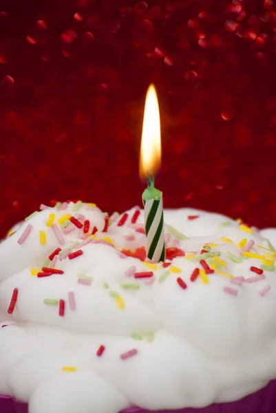 Cupcake avec une bougie allumée sur fond rouge vif — Photo