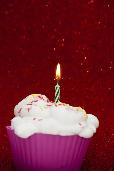 Cupcake mit brennender Kerze auf leuchtend rotem Hintergrund — Stockfoto