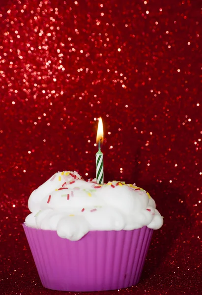 Cupcake con una candela accesa su sfondo rosso brillante — Foto Stock