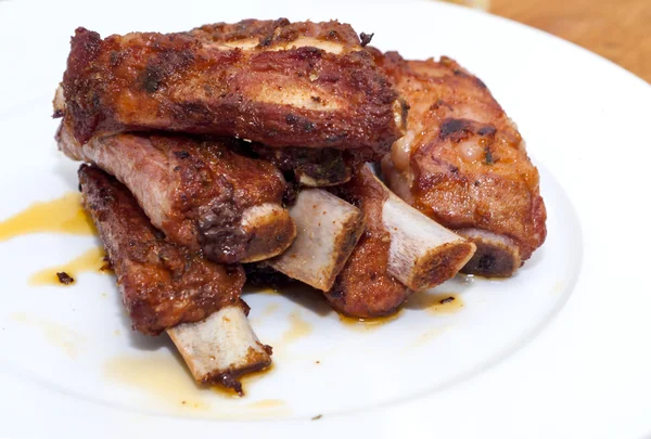 Côtes de porc rôties sur une assiette blanche — Photo