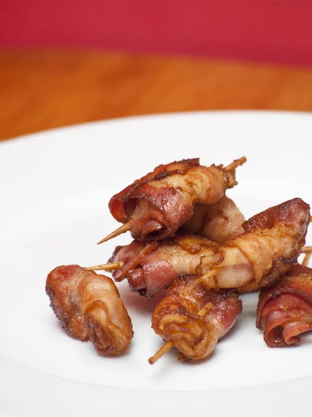 Rollos de rodajas de tocino cocido sujeto con un palillo — Foto de Stock