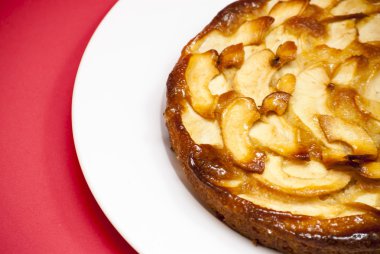 Elmalı turta kırmızı arka plan ile beyaz bir plaka üzerinde