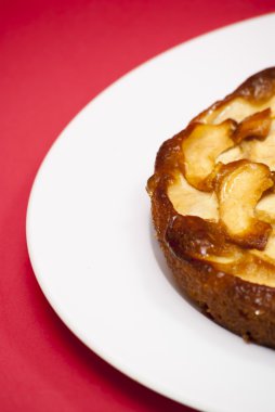 Elmalı turta kırmızı arka plan ile beyaz bir plaka üzerinde
