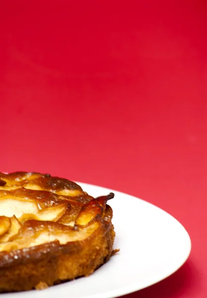 Tarte aux pommes sur une assiette blanche avec fond rouge — Photo