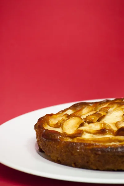 Tarte aux pommes sur une assiette blanche avec fond rouge — Photo