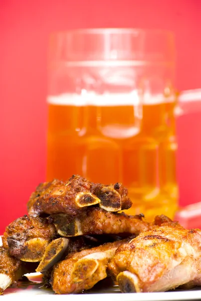 Costillas de cerdo asadas en un plato blanco con una jarra de cerveza al lado — Foto de Stock