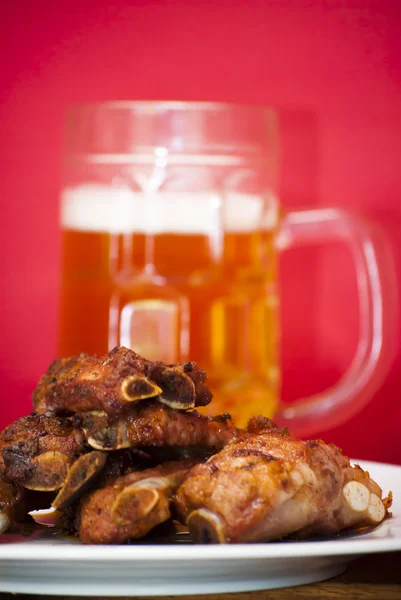 Costillas de cerdo asadas en un plato blanco con una jarra de cerveza al lado —  Fotos de Stock