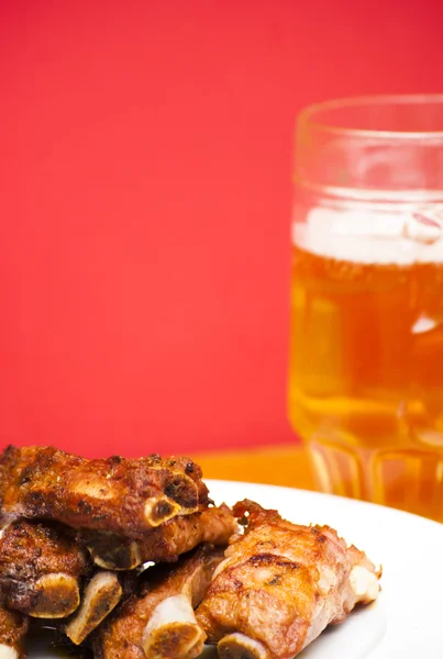 Geroosterde varkensvlees ribben volgende op een witte plaat met een kruik van bier — Stockfoto