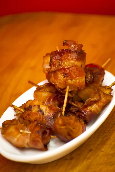 Rullar av skivor av kokta bacon ämne med en tandpetare på en wh — Stockfoto