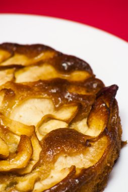 Elmalı turta kırmızı arka plan ile beyaz bir plaka üzerinde