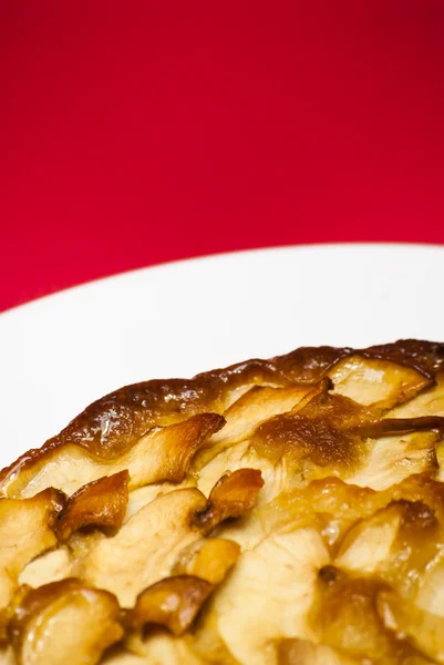 Tarte aux pommes sur une assiette blanche avec fond rouge — Photo