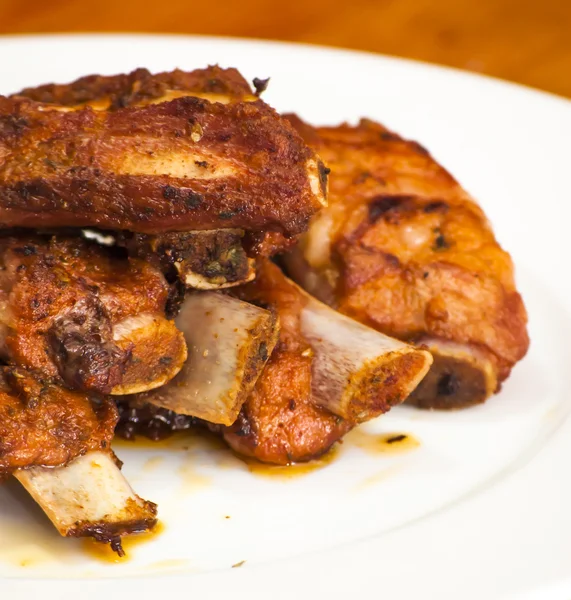 Жареные свиные ребрышки на белой тарелке — стоковое фото