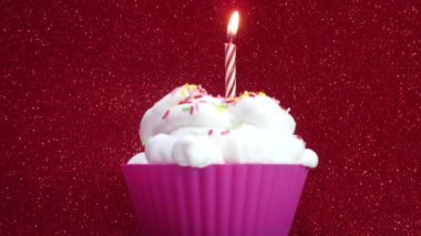 Parlak kırmızı bir arka plan üzerine de mum ile cupcake