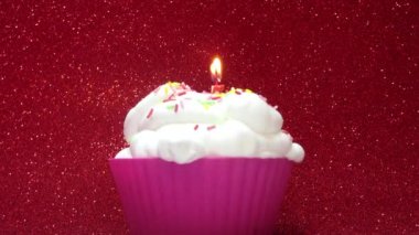 Parlak kırmızı bir arka plan üzerine de mum ile cupcake