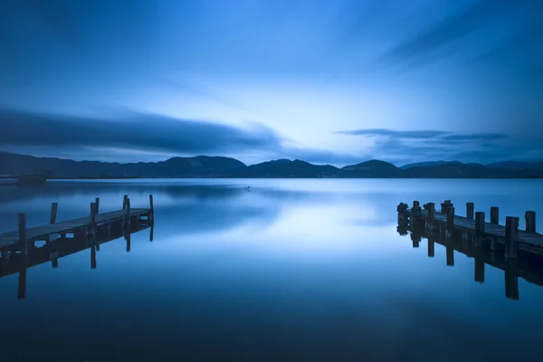 Two Wooden pier or jetty and on a blue lake sunset and sky refle — Stock Photo, Image