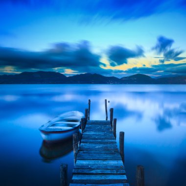 Wooden pier or jetty and a boat on a lake sunset. Versilia Tusca clipart